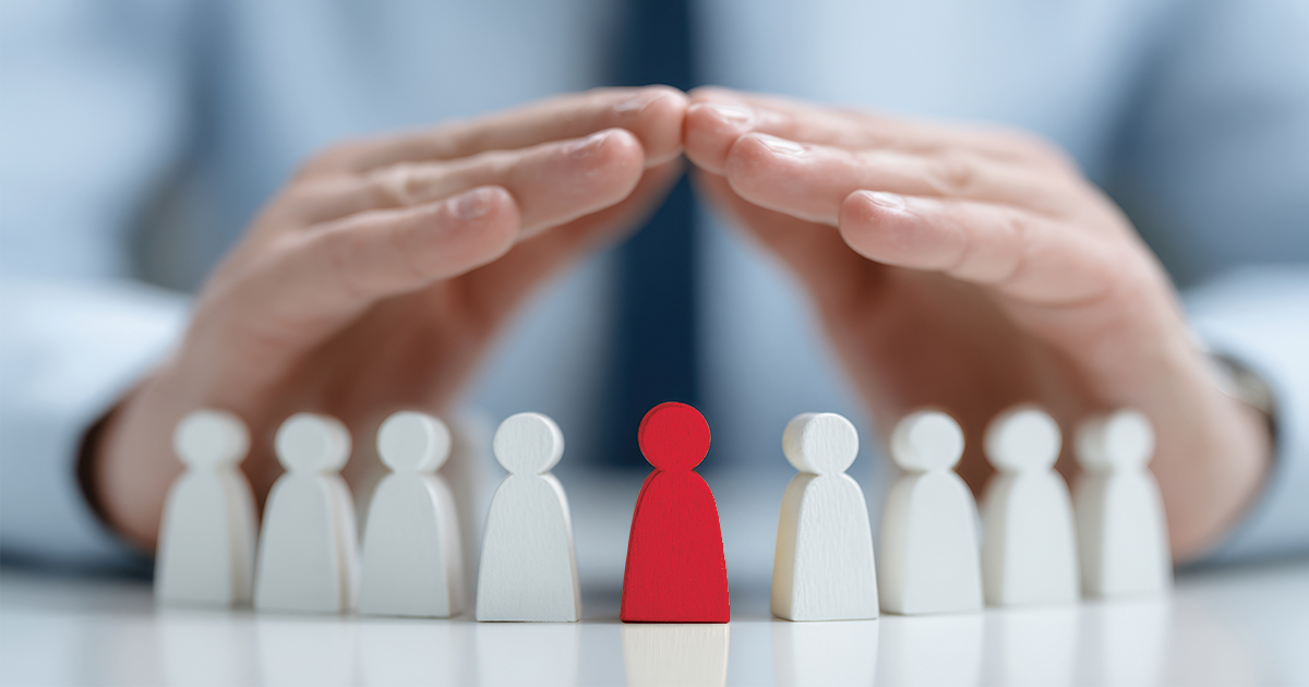 Holzfiguren von Menschen Symbolen, die die Hände eines Geschäftsmannes von oben bedecken