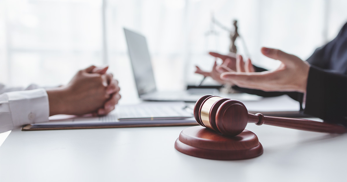 Männlicher Anwalt bei der Arbeit, Geschäftsleute und Anwälte besprechen Vertragsunterlagen mit einer Messingwaage auf einem Holztisch am Arbeitsplatz. Recht, Rechtsdienstleistungen, Beratung, Konzept der Gerechtigkeit.